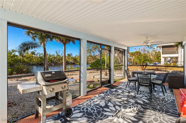 sunroom with ceiling fan and a water view