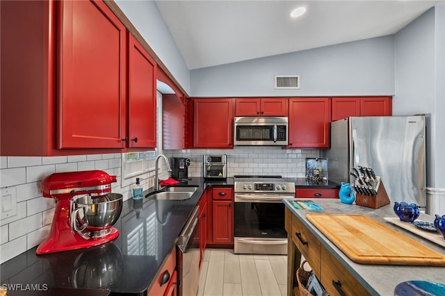 kitchen with lofted ceiling, sink, light hardwood / wood-style flooring, stainless steel appliances, and decorative backsplash