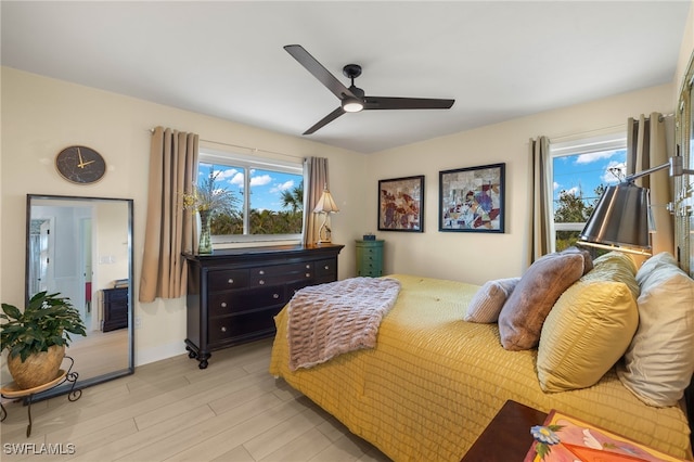 bedroom featuring ceiling fan, light hardwood / wood-style floors, and multiple windows