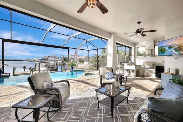 view of patio / terrace with ceiling fan, exterior kitchen, a water view, glass enclosure, and grilling area