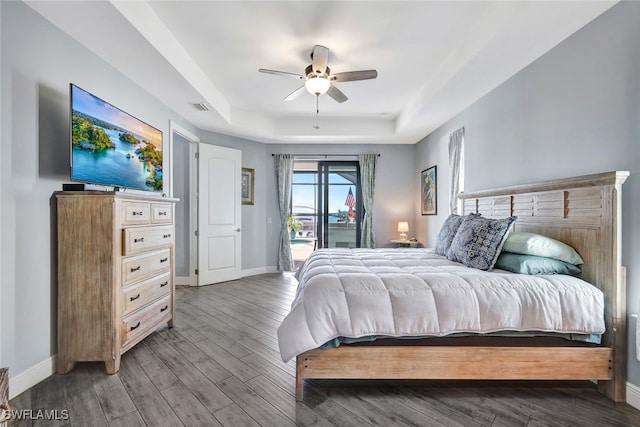 bedroom with a raised ceiling, access to exterior, ceiling fan, and hardwood / wood-style floors