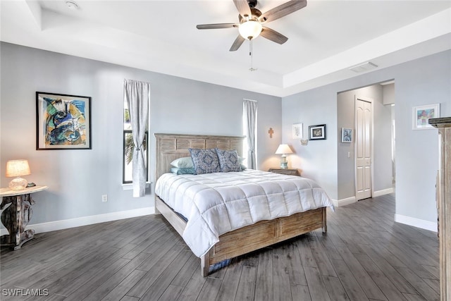 bedroom with a tray ceiling, ceiling fan, a closet, and dark wood-type flooring