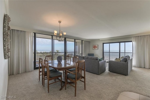 carpeted dining space with a wealth of natural light, a water view, and a chandelier