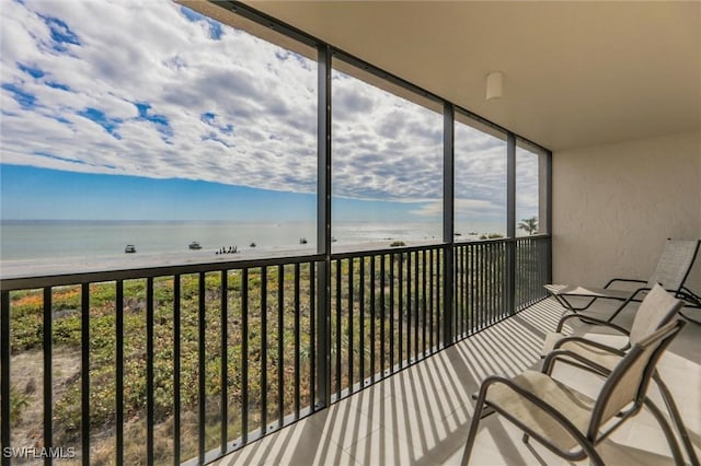 unfurnished sunroom featuring a water view and a beach view