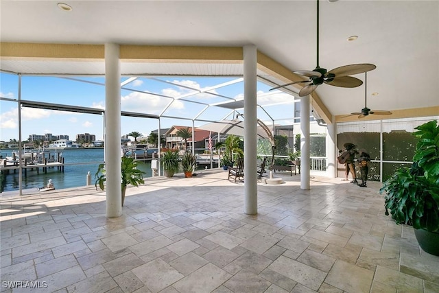 view of patio with glass enclosure, ceiling fan, and a water view