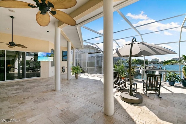 view of patio with a water view, ceiling fan, and a lanai