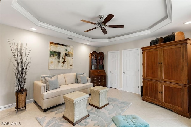 living room with ceiling fan and a raised ceiling