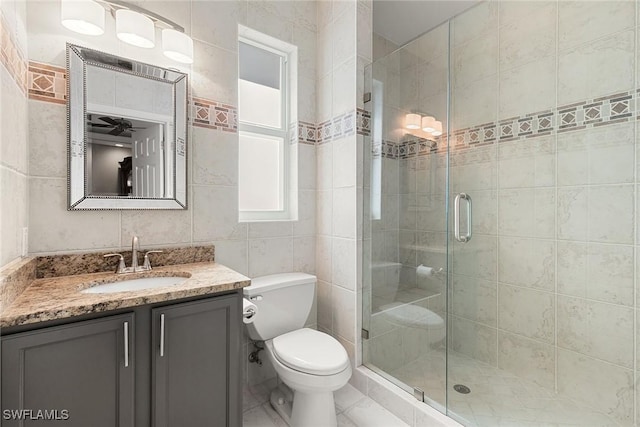 bathroom featuring toilet, vanity, tile walls, and walk in shower