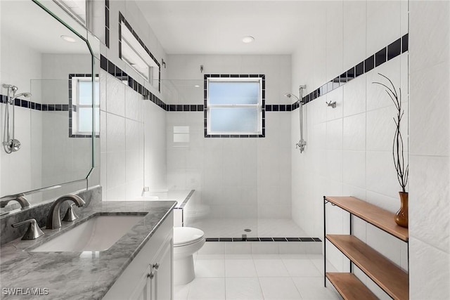 bathroom with tile patterned flooring, a tile shower, toilet, and tile walls