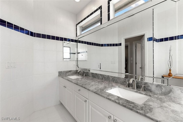 bathroom featuring tile patterned flooring, vanity, a healthy amount of sunlight, and tile walls