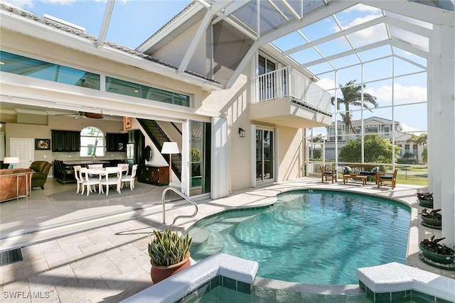 back of house with glass enclosure, ceiling fan, a balcony, and a patio