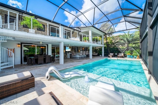 view of swimming pool featuring ceiling fan, a patio area, an outdoor living space, and glass enclosure