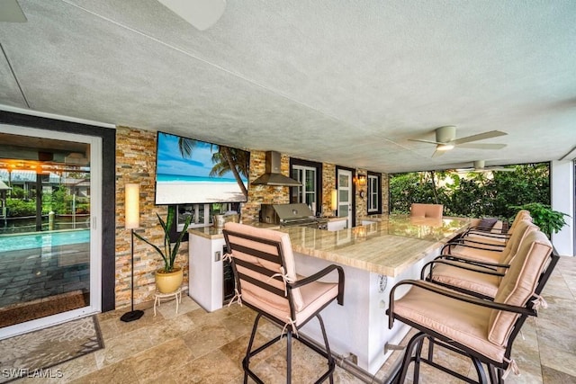 view of patio featuring an outdoor kitchen, an outdoor bar, grilling area, and ceiling fan