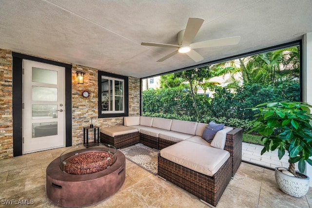 view of patio / terrace featuring ceiling fan and an outdoor living space with a fire pit