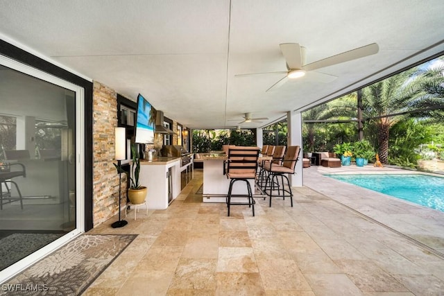 view of patio / terrace featuring a bar, area for grilling, ceiling fan, and a lanai