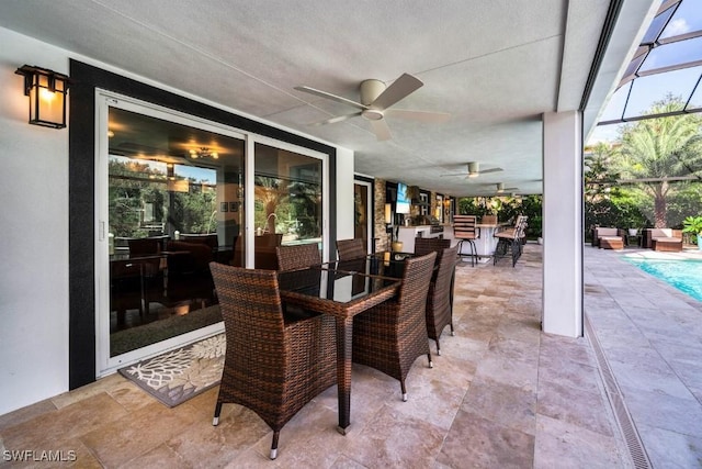 view of patio featuring ceiling fan and glass enclosure