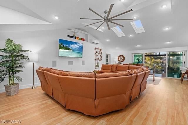 living room with light wood-type flooring, lofted ceiling with skylight, ceiling fan, and a wall unit AC