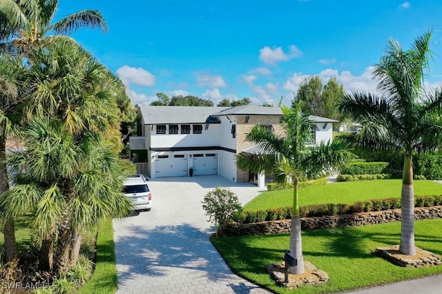 coastal inspired home featuring a garage and a front lawn