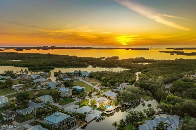 aerial view at dusk featuring a water view