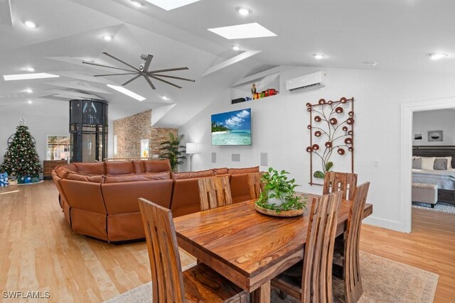 dining room featuring an AC wall unit, lofted ceiling with skylight, light hardwood / wood-style flooring, and ceiling fan