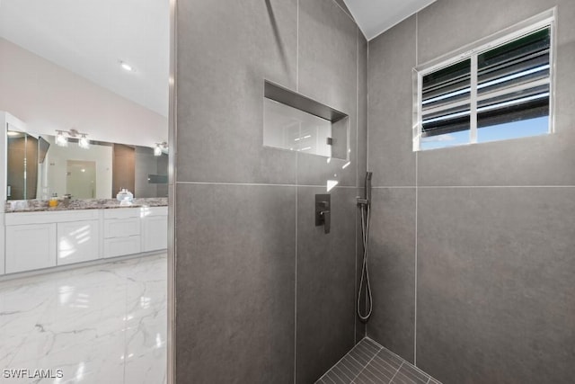 bathroom with vanity, lofted ceiling, and tiled shower