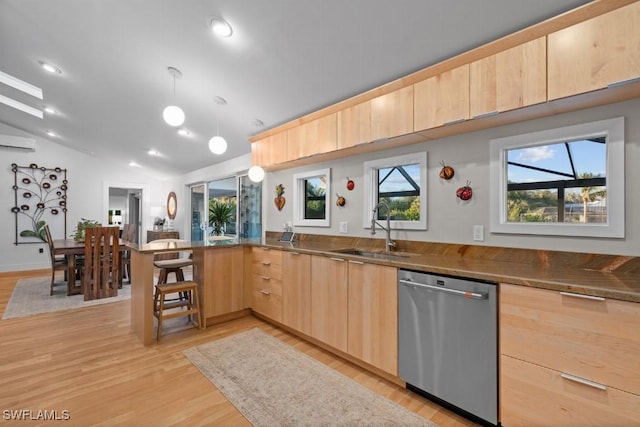 kitchen with light brown cabinets, stainless steel dishwasher, kitchen peninsula, pendant lighting, and vaulted ceiling