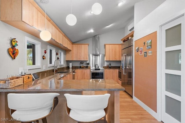 kitchen featuring sink, hanging light fixtures, wall chimney range hood, kitchen peninsula, and lofted ceiling