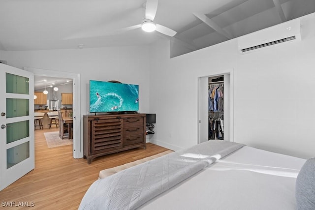 bedroom with ceiling fan, an AC wall unit, vaulted ceiling, a closet, and hardwood / wood-style flooring