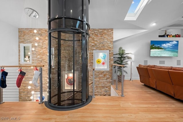 interior space featuring vaulted ceiling with skylight and light wood-type flooring