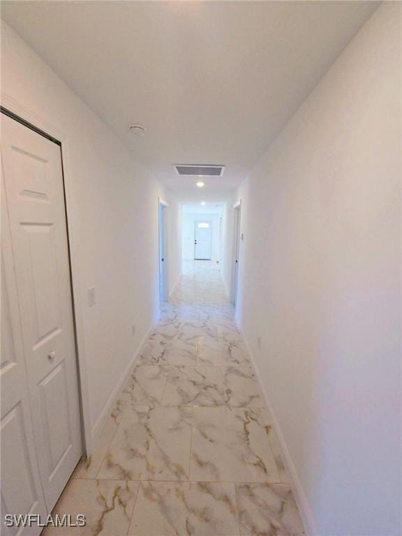 hallway with marble finish floor, visible vents, and baseboards