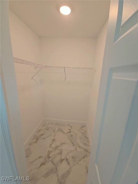 walk in closet featuring marble finish floor