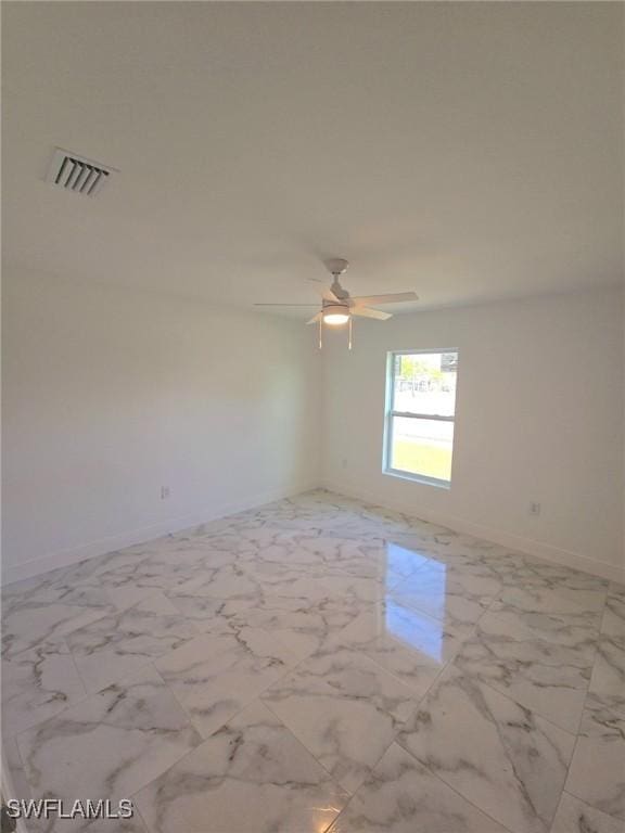 unfurnished room with ceiling fan, marble finish floor, visible vents, and baseboards