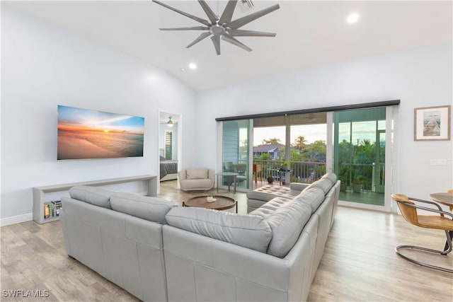 living room with ceiling fan, light hardwood / wood-style floors, and lofted ceiling