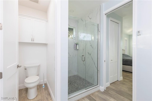 bathroom featuring hardwood / wood-style floors, toilet, and a shower with shower door