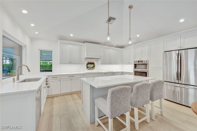 kitchen featuring white cabinets, sink, hanging light fixtures, a kitchen island, and stainless steel appliances