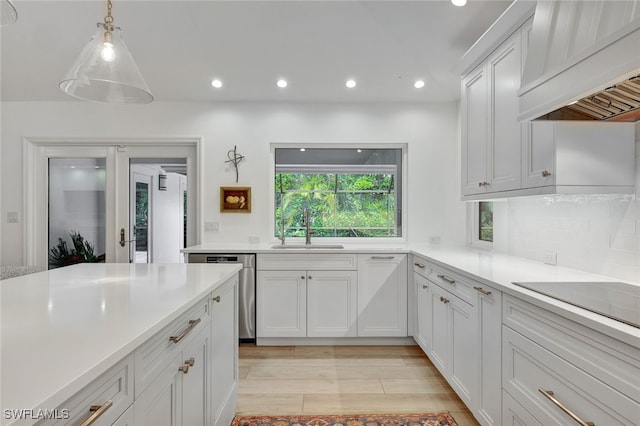 kitchen featuring white cabinets, decorative light fixtures, premium range hood, and sink