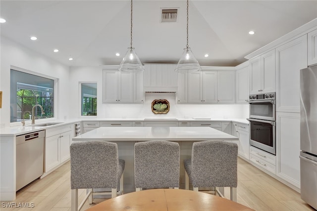 kitchen featuring a center island, stainless steel appliances, white cabinetry, and sink