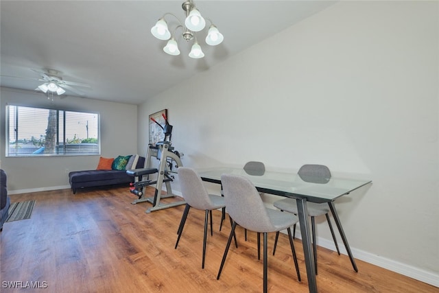 dining space featuring wood-type flooring and ceiling fan with notable chandelier