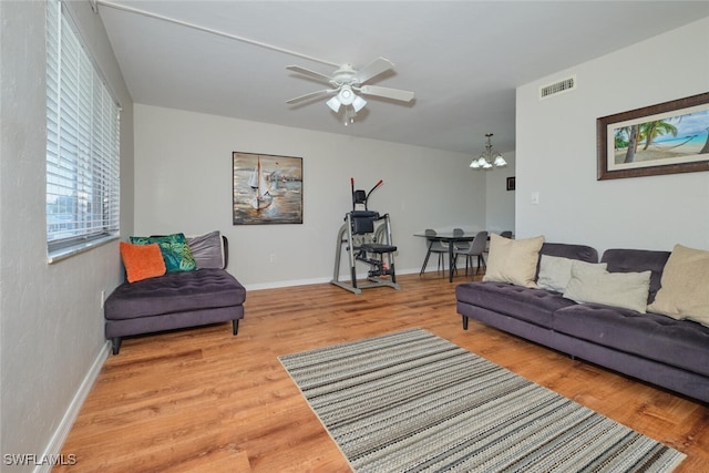 living room featuring wood-type flooring and ceiling fan with notable chandelier