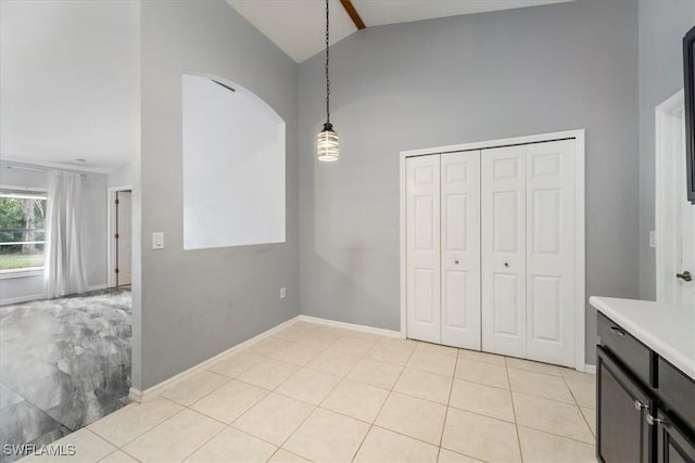 interior space featuring light tile patterned floors, high vaulted ceiling, and a closet