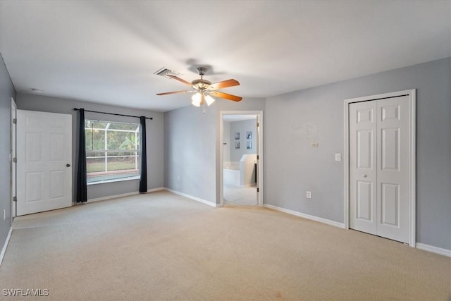 unfurnished bedroom with light carpet, connected bathroom, and ceiling fan