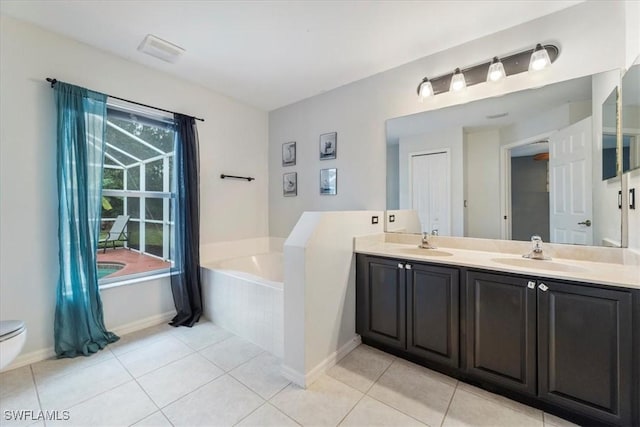 bathroom with tile patterned flooring, vanity, and a relaxing tiled tub