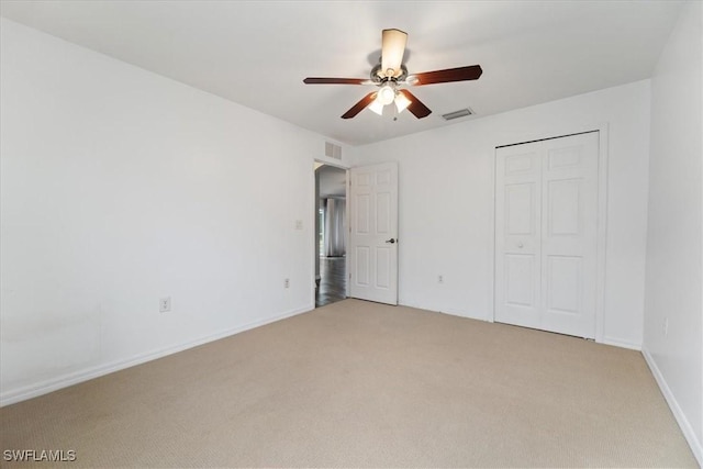 unfurnished bedroom with ceiling fan, light colored carpet, and a closet