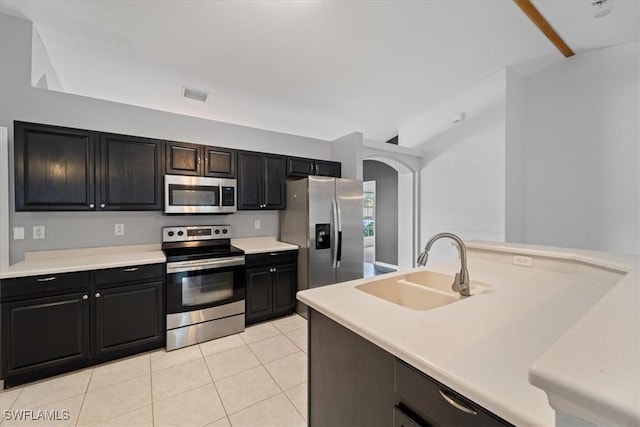 kitchen featuring sink, light tile patterned floors, stainless steel appliances, and lofted ceiling