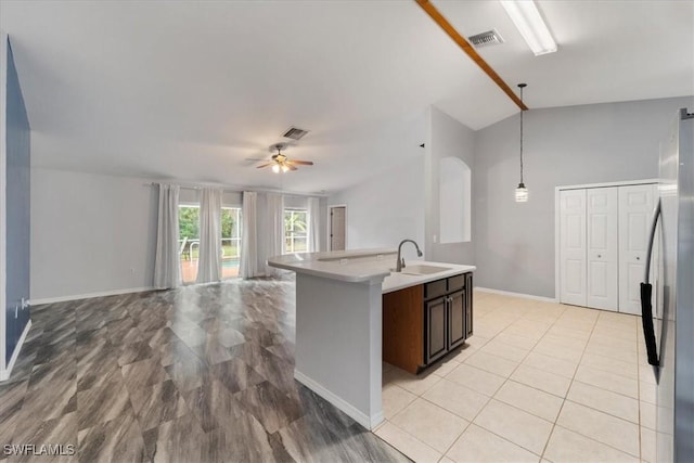 kitchen with sink, vaulted ceiling, ceiling fan, dark brown cabinetry, and stainless steel refrigerator