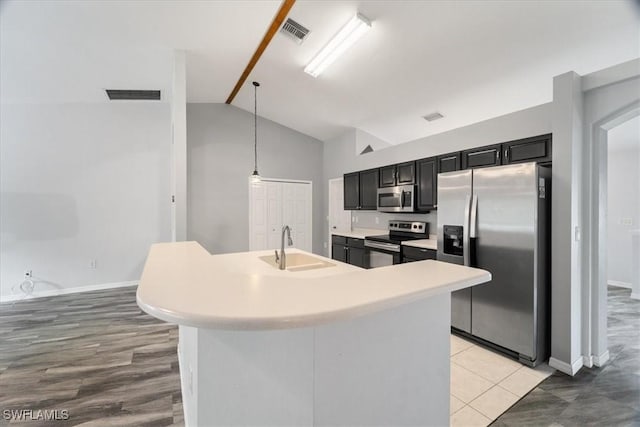 kitchen with sink, stainless steel appliances, an island with sink, pendant lighting, and vaulted ceiling