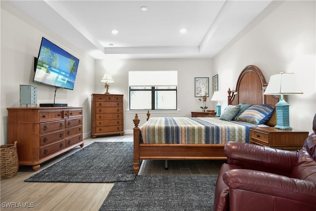 bedroom featuring a tray ceiling and wood-type flooring