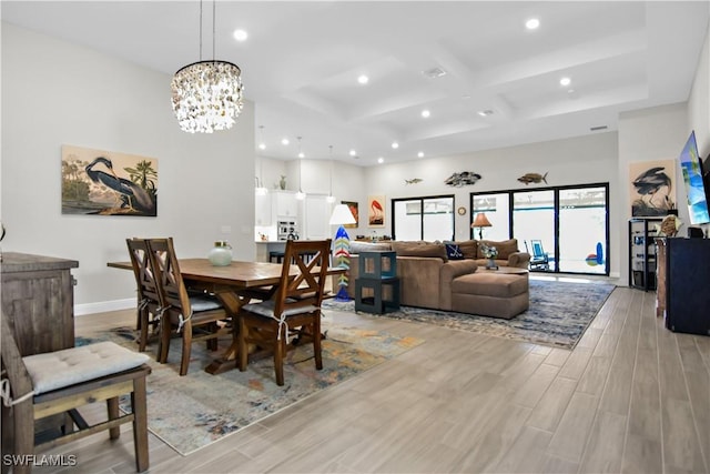 dining space featuring light wood-type flooring, an inviting chandelier, and coffered ceiling