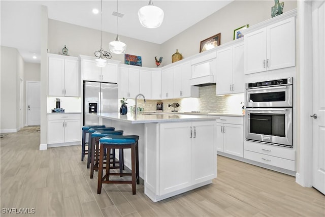 kitchen with white cabinetry, custom exhaust hood, decorative light fixtures, and appliances with stainless steel finishes