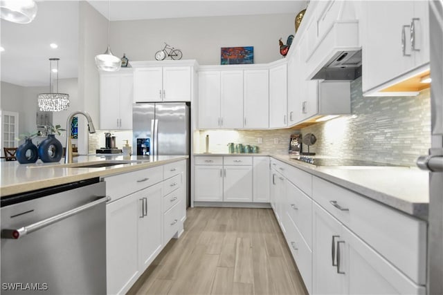 kitchen featuring white cabinets, stainless steel appliances, light hardwood / wood-style flooring, and hanging light fixtures